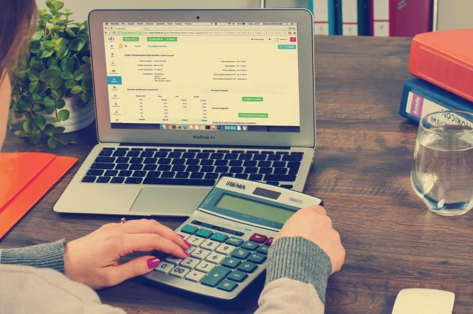 Contador trabajando con calculadora y estados financieros en su escritorio