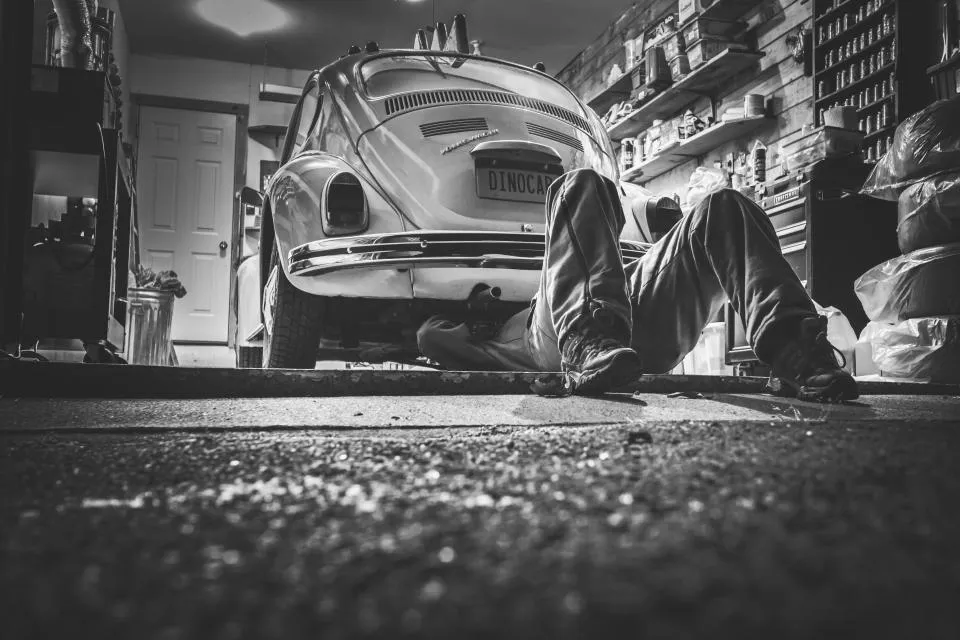 Mecánico revisando un vehículo elevado dentro de un taller automotriz